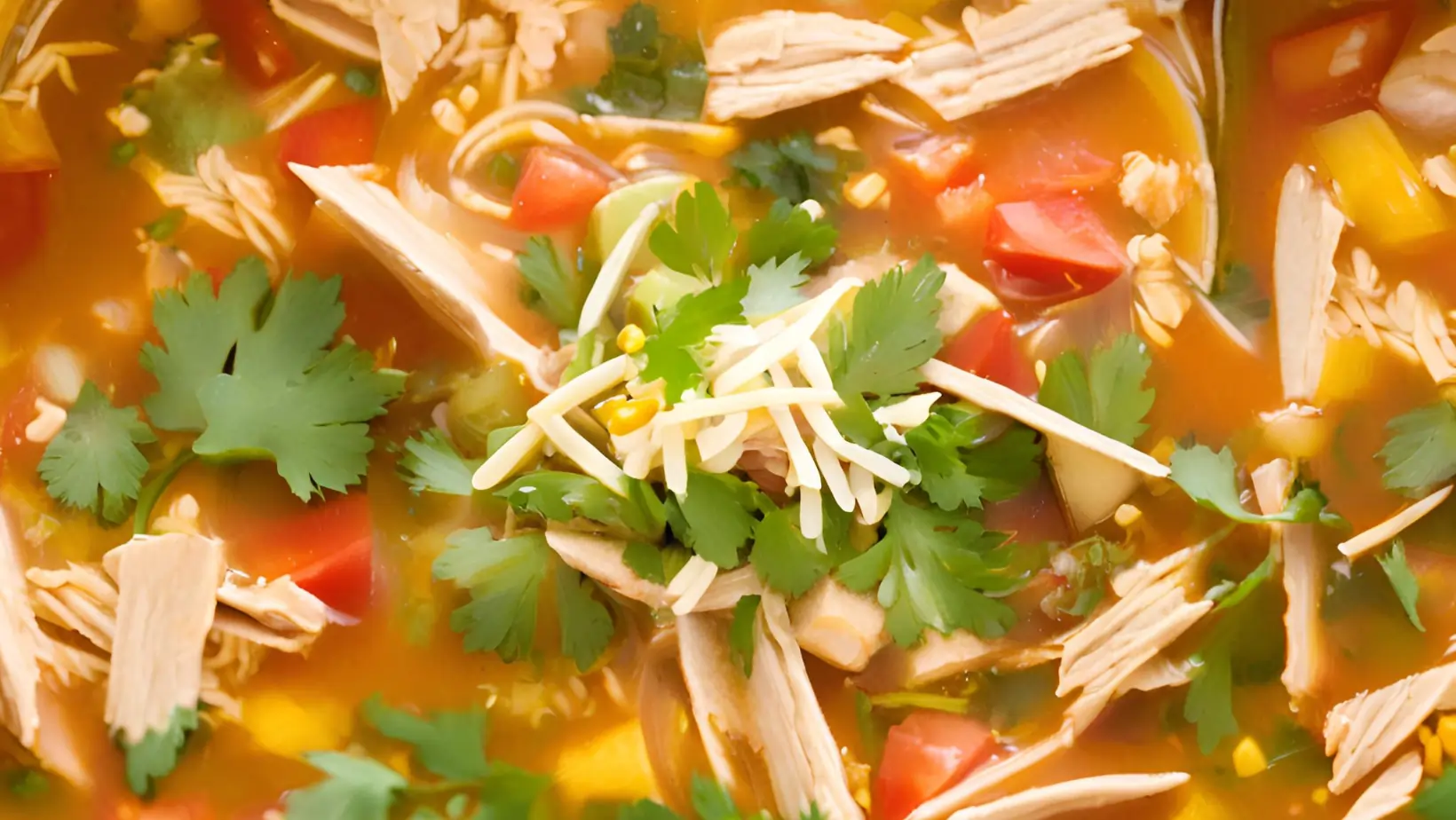 Bowl of gluten-free chicken tortilla soup with toppings like tortilla strips and avocado.