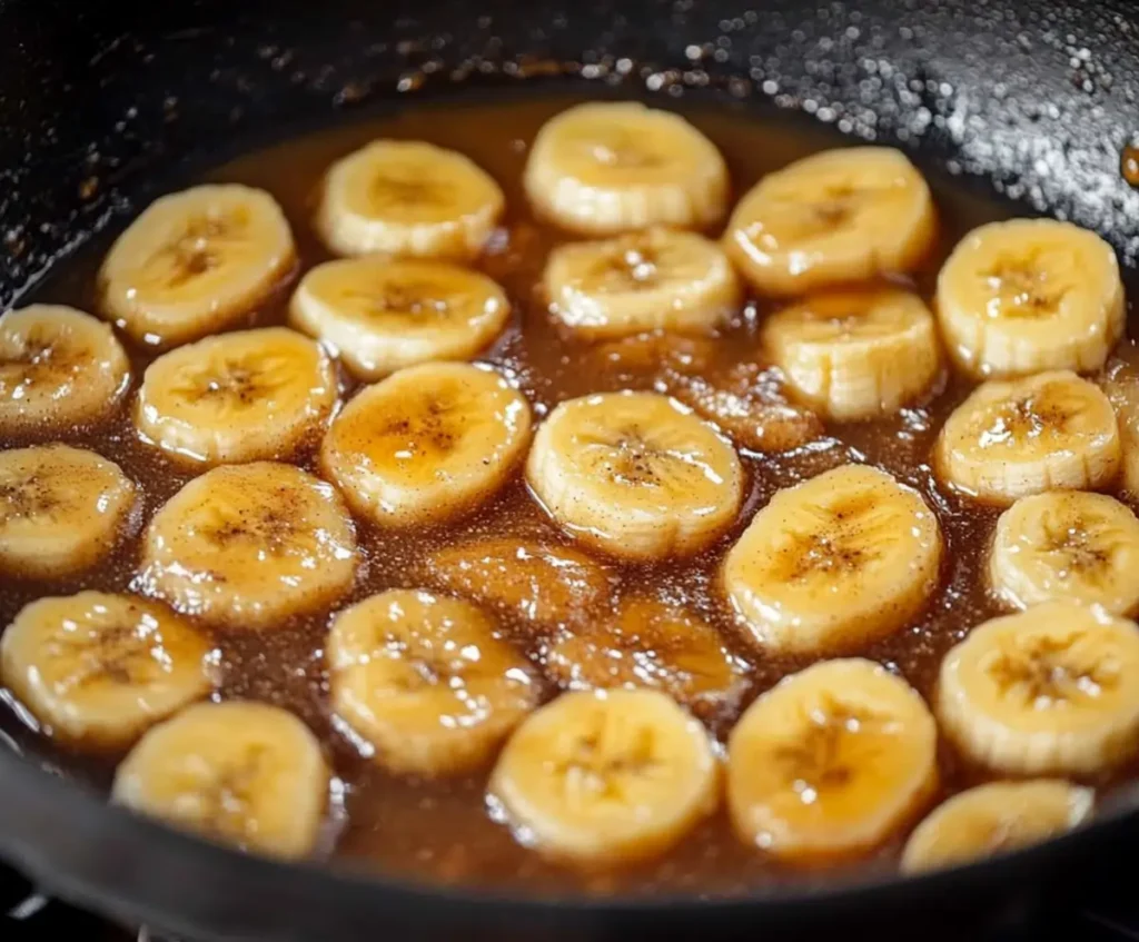 Sliced bananas caramelizing in a bubbling brown sugar and butter sauce for Bananas Foster French Toast.