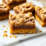 A stack of pumpkin bars with chai caramel and a crumbly streusel topping, showcasing a soft pumpkin base and rich caramel layer.